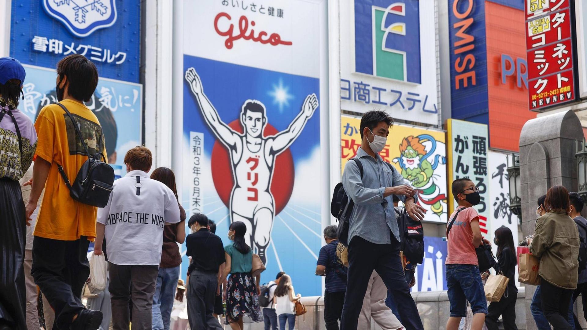 Fußgänger in Osaka gehen mit Mundschutz spazieren. Fußgänger in Osaka gehen mit Mundschutz spazieren.