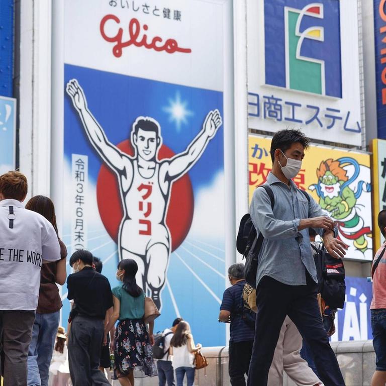 Fußgänger in Osaka gehen mit Mundschutz spazieren.