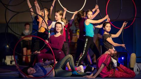 Das Foto zeigt Schülerinnen der fünften Klasse der Dresdner Waldorfschule, die beim Zirkus-Unterricht in einer Turnhalle mit Hula-Hoop-Reifen üben.
