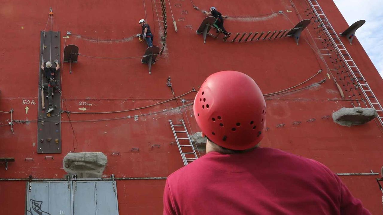 Sportler erproben ihr Können an einer Kletterwand. Sportler erproben ihr Können an einer Kletterwand.