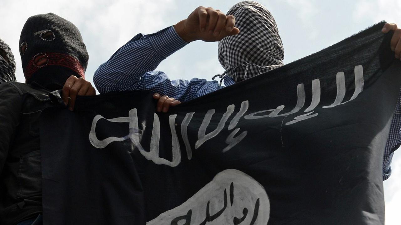 Unterstützer der Extremistenmiliz Islamischer Staat (IS) mit Fahne. Unterstützer der Extremistenmiliz Islamischer Staat (IS) mit Fahne.