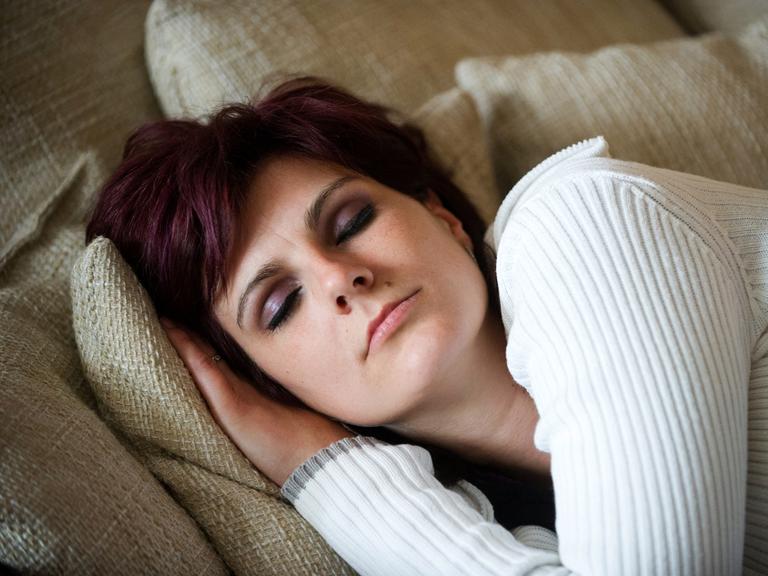 Junge Frau ruht schlafend auf dem Sofa.