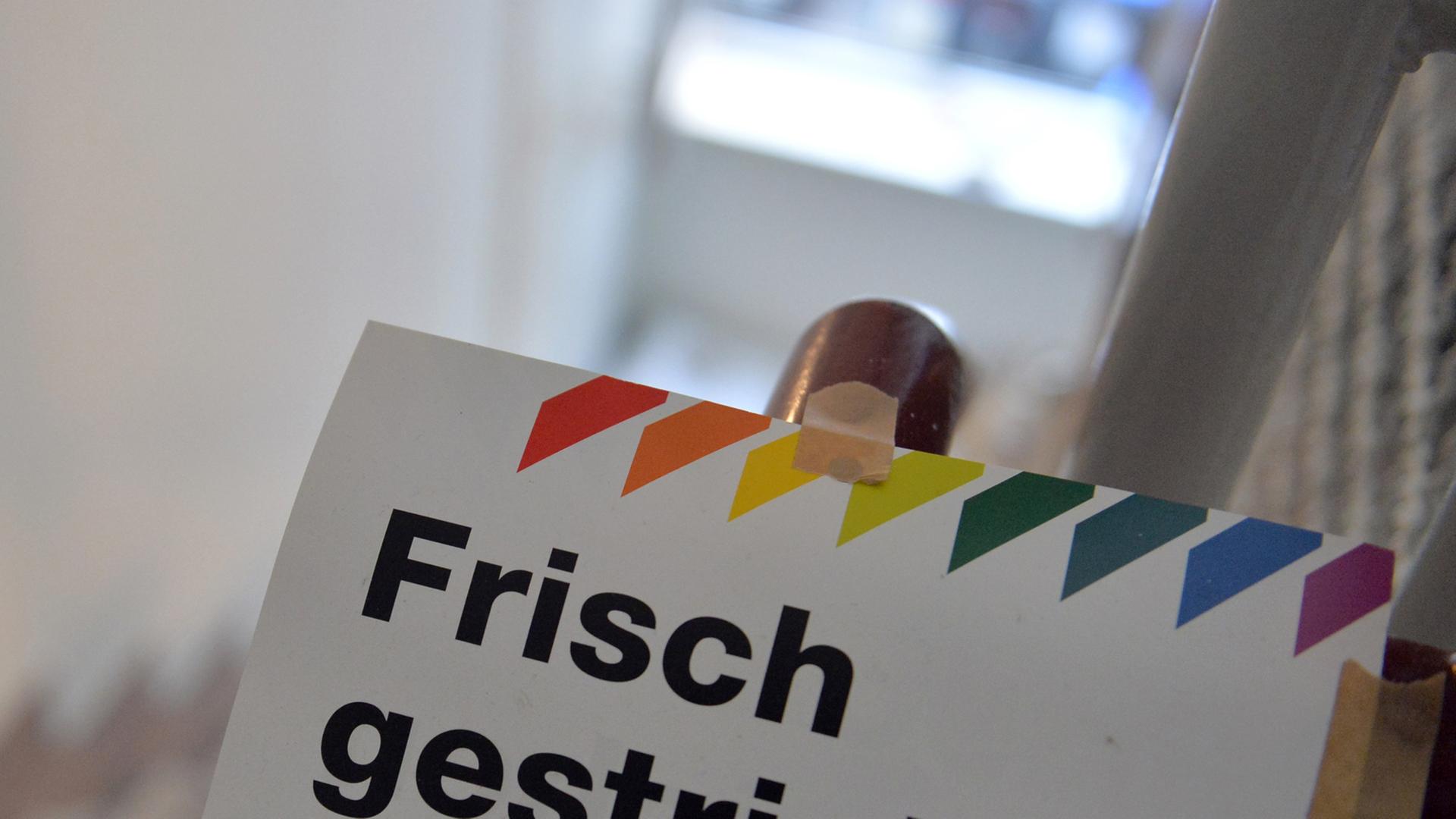 Ein Schild mit der Aufschrift "Frisch gestrichen" klebt an einem Treppengeländer. Ein Schild mit der Aufschrift "Frisch gestrichen" klebt an einem Treppengeländer.