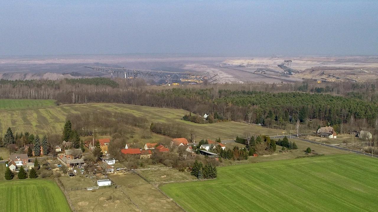 Blick über die Dächer des Ortes Proschim auf den Braunkohletagebau Welzow-Süd der Lausitz Energie Bergbau AG.