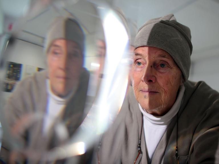 Die Künstlerin Mary Bauermeister betrachtet am Donnerstag (19.04.2012) in Bonn eines ihrer Kristall-Objekte.