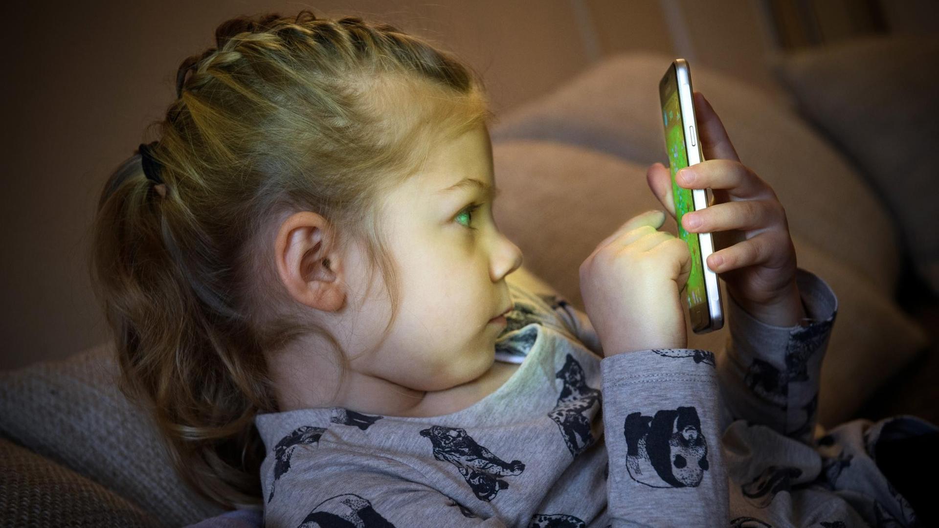 Ein kleines Mädchen spielt auf einem Smartphone. Ein kleines Mädchen spielt auf einem Smartphone.