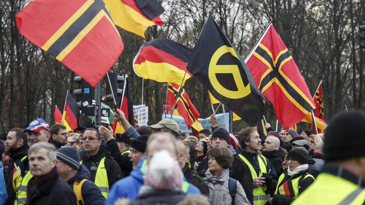 Aus einer Menschenmenge ragen schwarz-rot-goldene Flaggen und eine der Identitären Bewegung. Aus einer Menschenmenge ragen schwarz-rot-goldene Flaggen und eine der Identitären Bewegung.