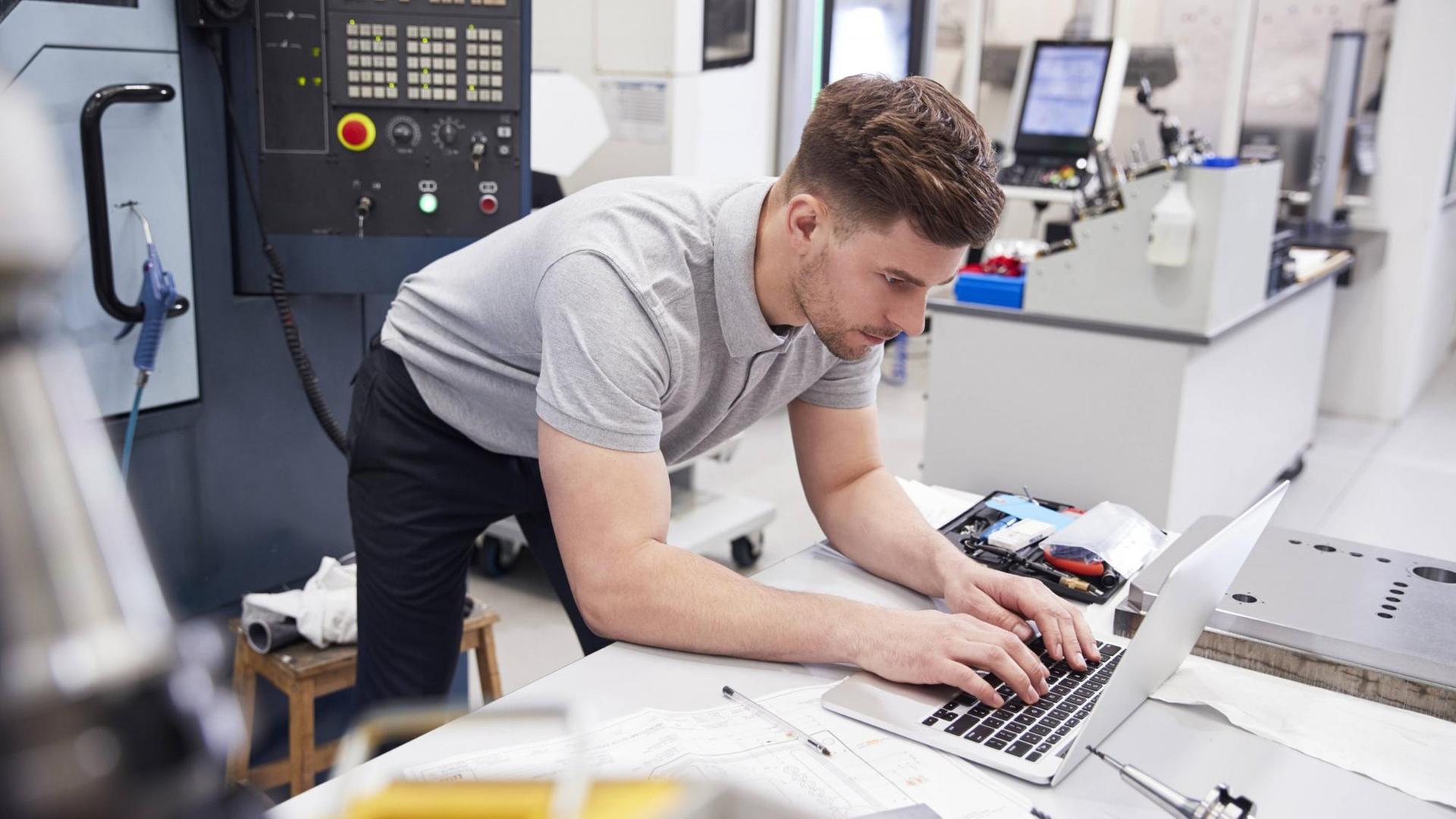 Ein junger Mann steht am Laptop in einem Technologizentrum Ein junger Mann steht am Laptop in einem Technologizentrum
