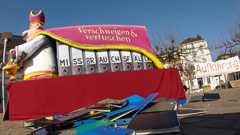 Ein Karnevalswagen des Düsseldorfer Rosenmontagszuges mit der Aufschrift "Verschweigen & Vertuschen" steht am 18.02.2013 vor dem Dom in Trier (Rheinland-Pfalz).