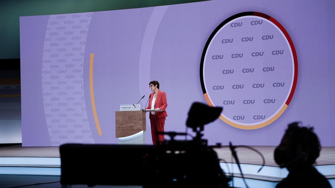 Die scheidende CDU-Vorsitzende Annegret Kramp-Karrenbauer spricht beim digitalen Bundesparteitag der CDU. Im Vordergrund ist der Schatten einer Fernsehkamera zu sehen. Die scheidende CDU-Vorsitzende Annegret Kramp-Karrenbauer spricht beim digitalen Bundesparteitag der CDU. Im Vordergrund ist der Schatten einer Fernsehkamera zu sehen.