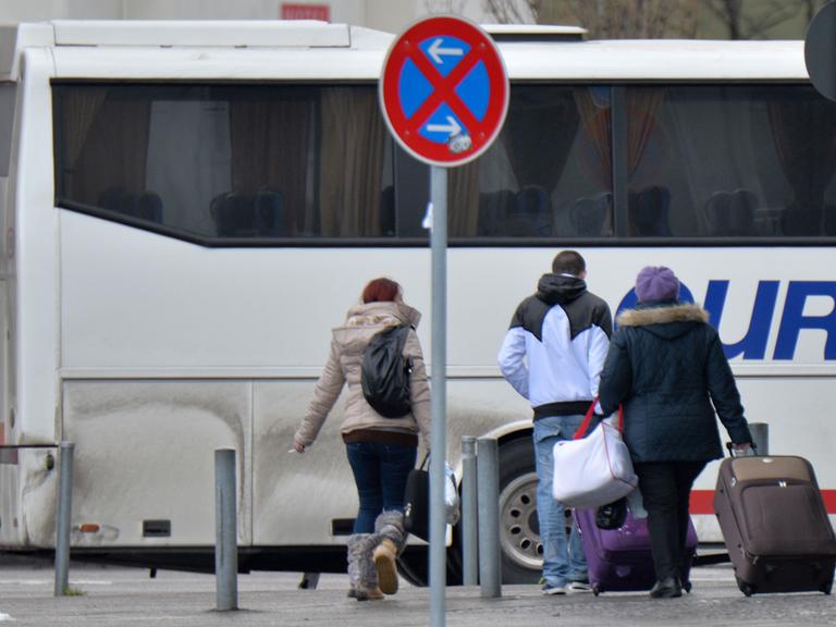 Fahrgäste eines aus Rumänien eingetroffenen Reisebusses gehen am 08.01.2014 in Berlin an einer Haltestelle des Zentralen Omnibusbahnhofes Berlin (ZOB) mit ihren Koffern zum Ausgang.