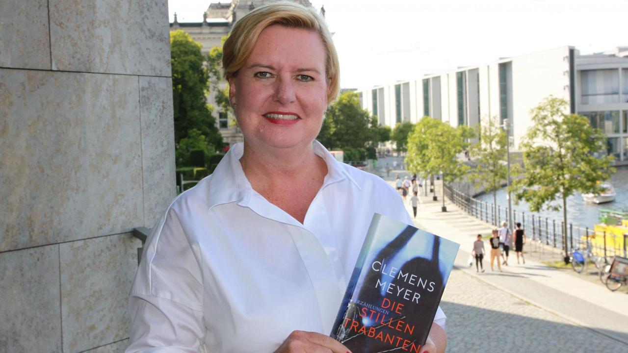 Eva Högl steht vor einem Gebäude im Regierungsviertel. In ihren Händen das Buch "Die stillen Trabanten".