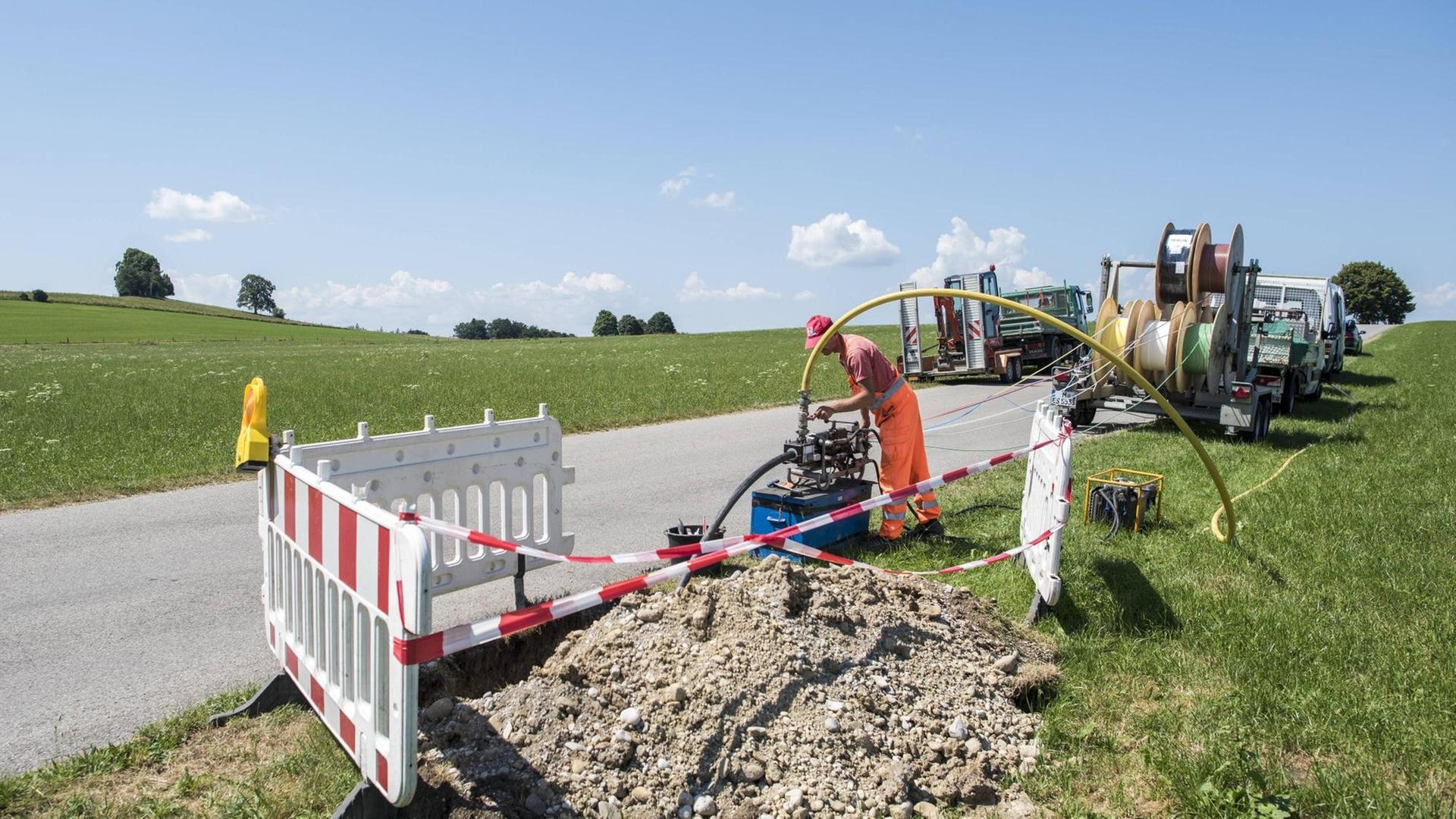 Ein Arbeiter verlegt bei Degerndorf in Bayern ein Glasfaserkabel