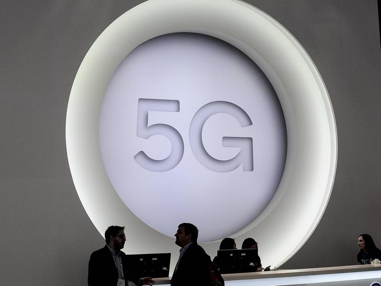 Menschen stehen beim Mobile World Congress in Barcelona vor einem riesigen 5G-Logo.