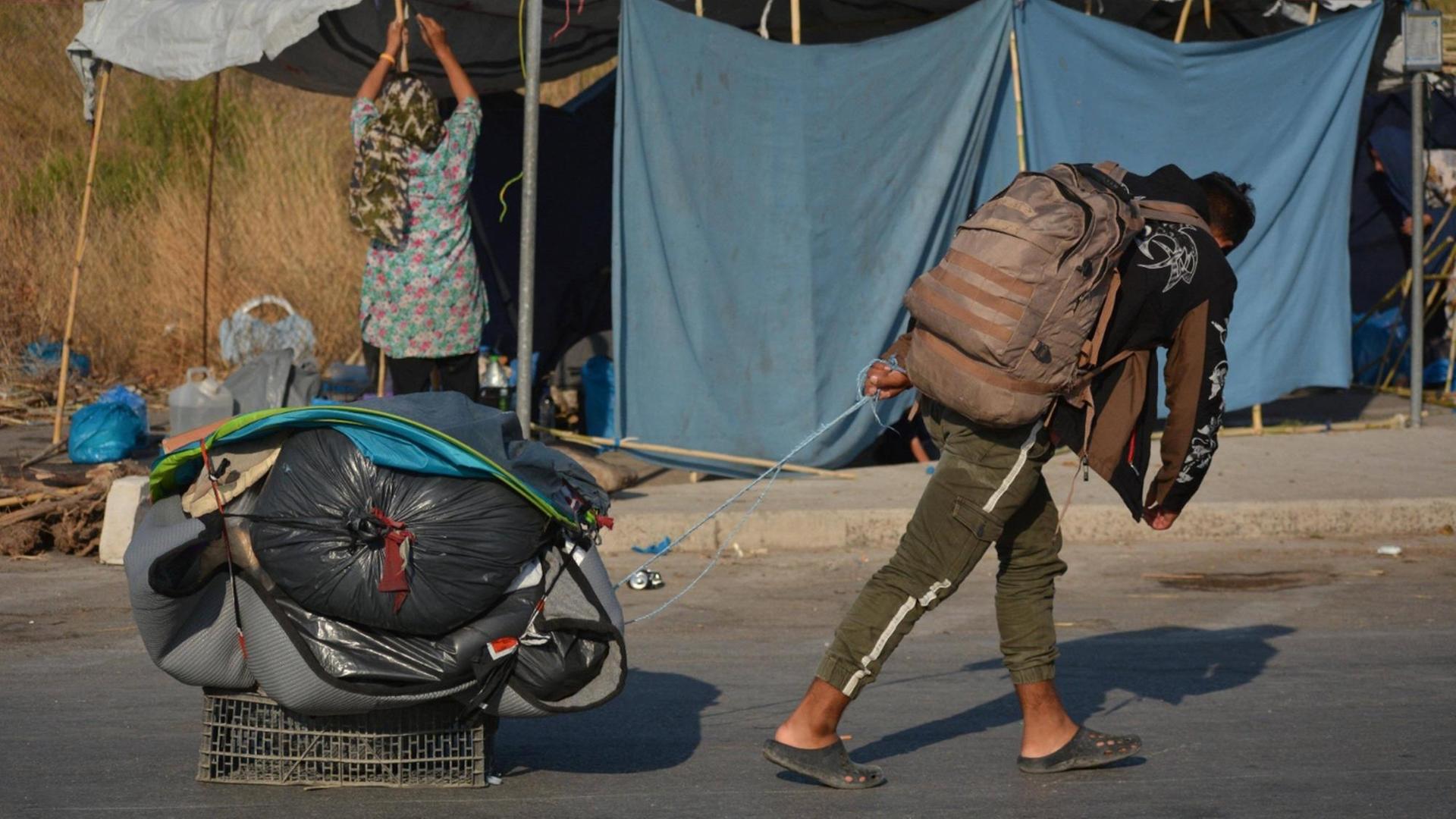 Ein Migrant auf Lesbos zieht seine verpackten Habseligkeiten in einer Kiste über die Straße.