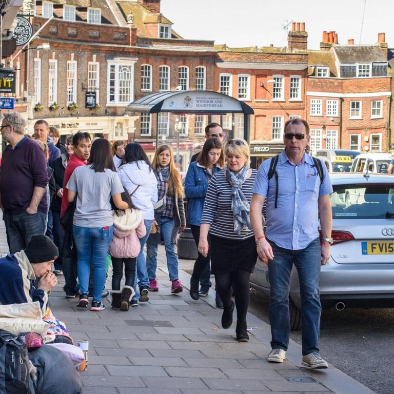 Passanten gehen an einem Obdachlosen auf der High Street in Windsor vorbei