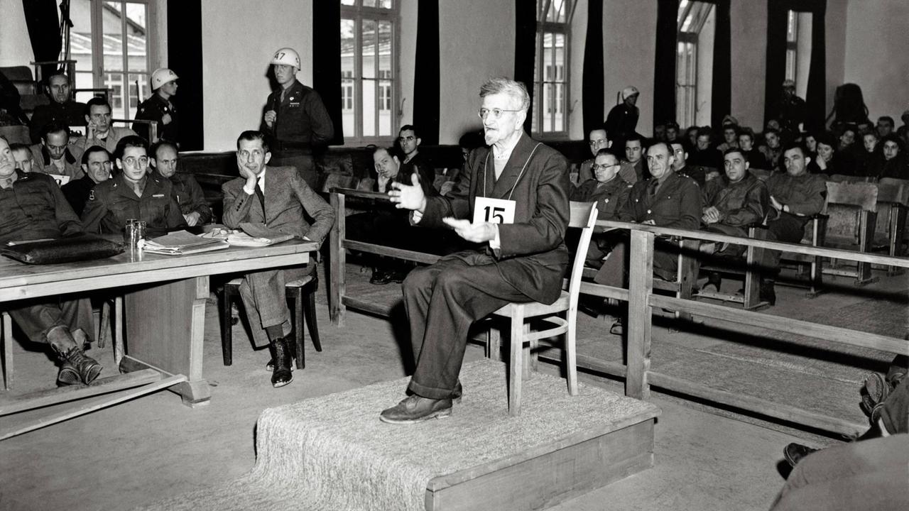 Dachauer Kriegsverbrecherprozess: Der Angeklagte Dr. Claus Schilling (Lagerarzt, der Malariaexperimente durchgeführt hat) sitzt auf dem Angeklagten-Stuhl vor einem U.S.-Militärgericht, im Saal Zuschauer und Wachpersonal. Schilling wurde am 13.12.1945 zum Tode verurteilt und am 29.05.1946 gehängt. 