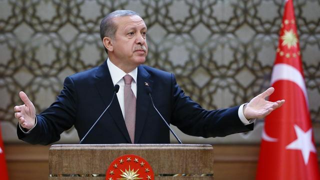 Der türkische Präsident Recep Tayyip Erdogan hält eine Rede, hinter ihm sind zwei türkische Flaggen zu sehen.