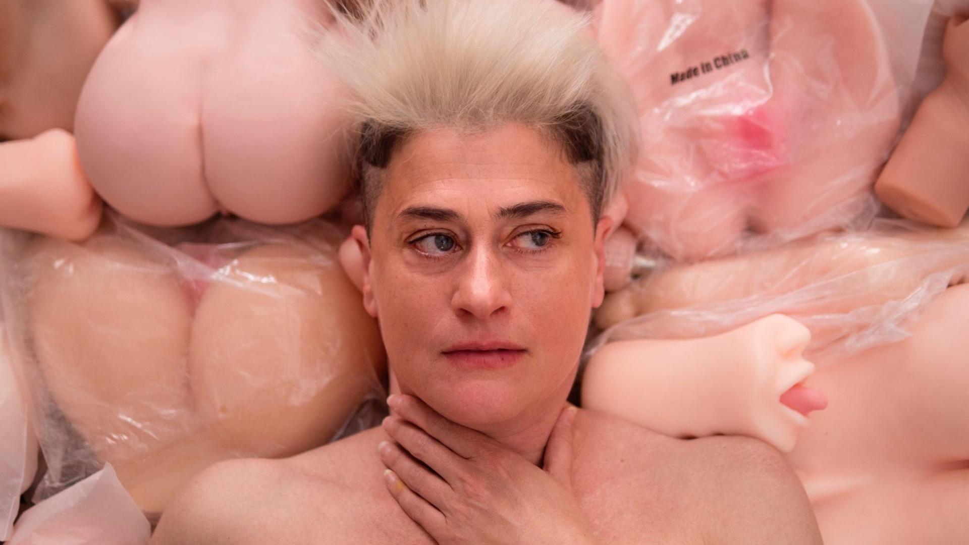 Auf dem Bild ist die Musikerin Peaches zu sehen. Hinter ihr befinden sich viele Sexpuppen. Auf dem Bild ist die Musikerin Peaches zu sehen. Hinter ihr befinden sich viele Sexpuppen.