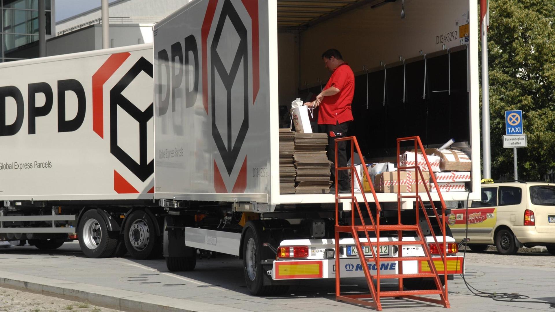 Ein Mitarbeiter steht im Laderaum eines Lastwagens mit dem DPD-Logo. Ein Mitarbeiter steht im Laderaum eines Lastwagens mit dem DPD-Logo.