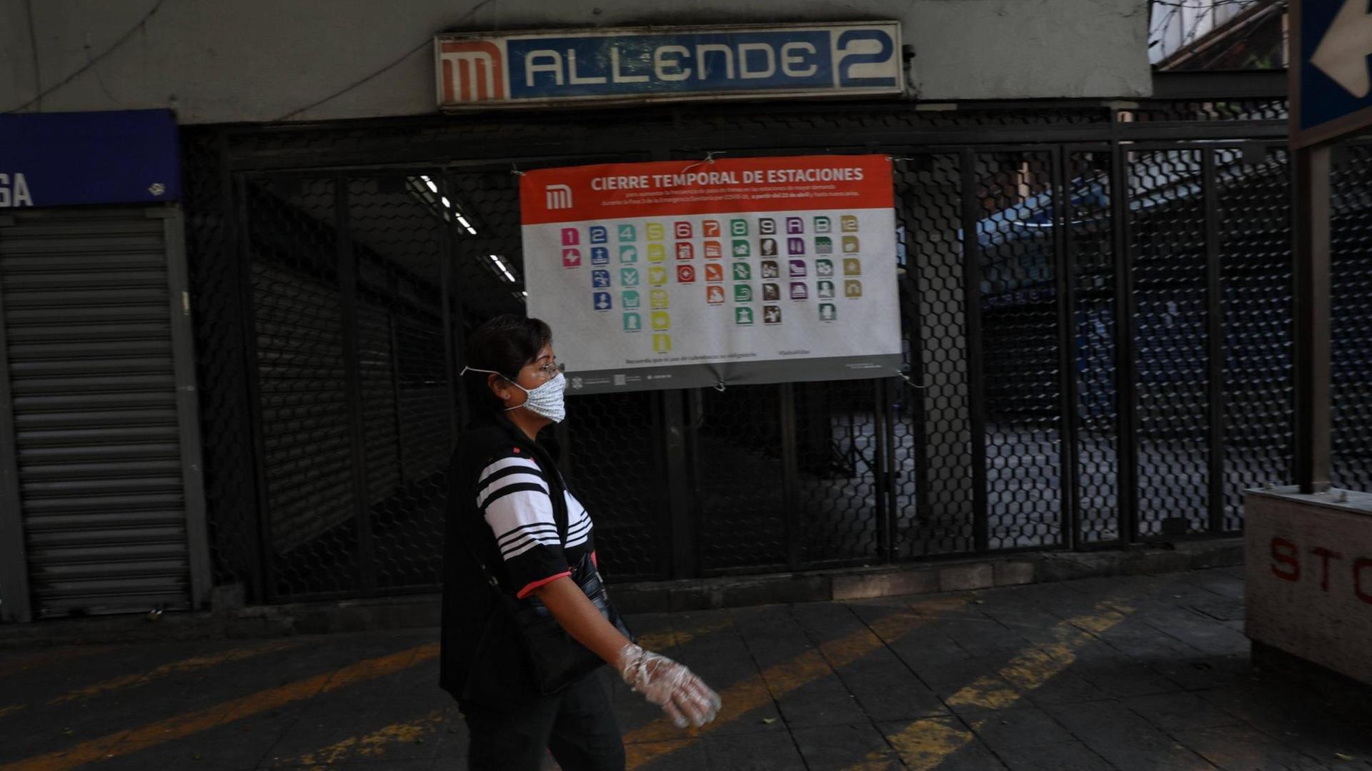 Eine Frau mit Maske und Handschuhen läuft an einer geschlossenen Metro-Station in Mexiko-Stadt vorbei. Eine Frau mit Maske und Handschuhen läuft an einer geschlossenen Metro-Station in Mexiko-Stadt vorbei.