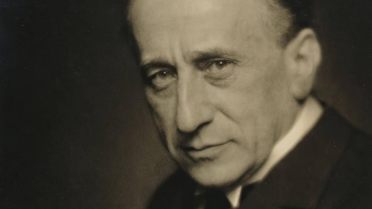 Auf einer nostalgisch-bräunlichen Fotografie ist ein ältere Mann mit freundlichen Augen und nach hinten gekämmten Haar zu sehen. Auf einer nostalgisch-bräunlichen Fotografie ist ein ältere Mann mit freundlichen Augen und nach hinten gekämmten Haar zu sehen.
