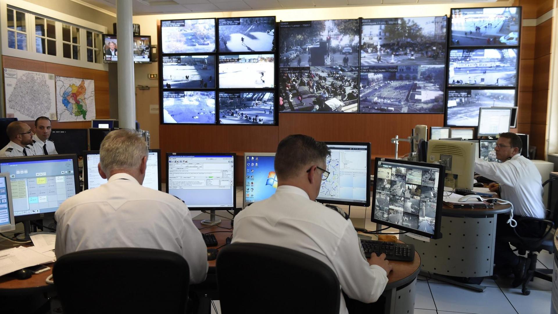 Polizisten vor Monitoren, die Bilder von Überwachungskameras zeigen Polizisten vor Monitoren, die Bilder von Überwachungskameras zeigen