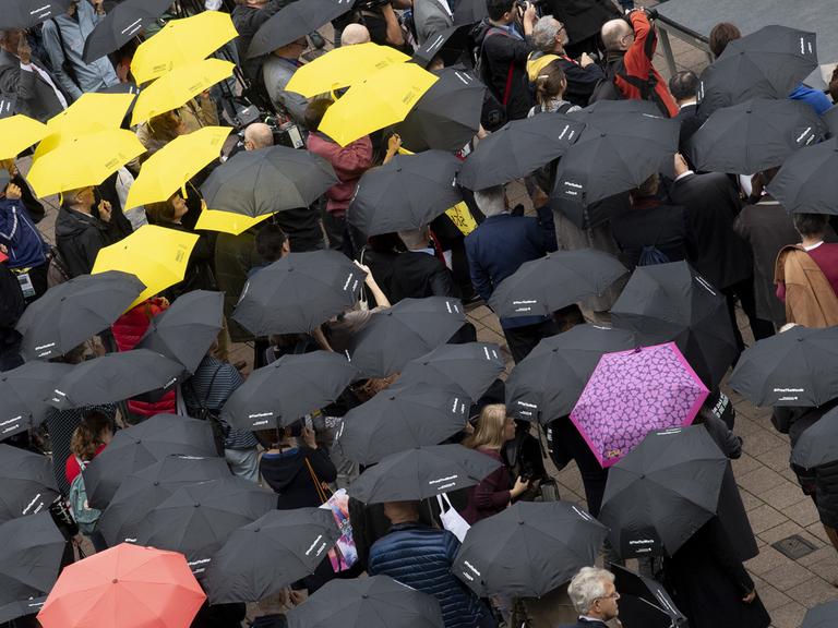 dpatopbilder - 17.10.2019, Hessen, Frankfurt/Main: Mit Regenschirmen beteiligen sich zahlreiche Menschen auf der Buchmesse an einer Mahnwache für die Meinungsfreiheit. Dabei ging es in erster Linie um ein Zeichen der Solidarität für den in China inhaftierten Autor Gui Minhai. Foto: Boris Roessler/dpa | Verwendung weltweit