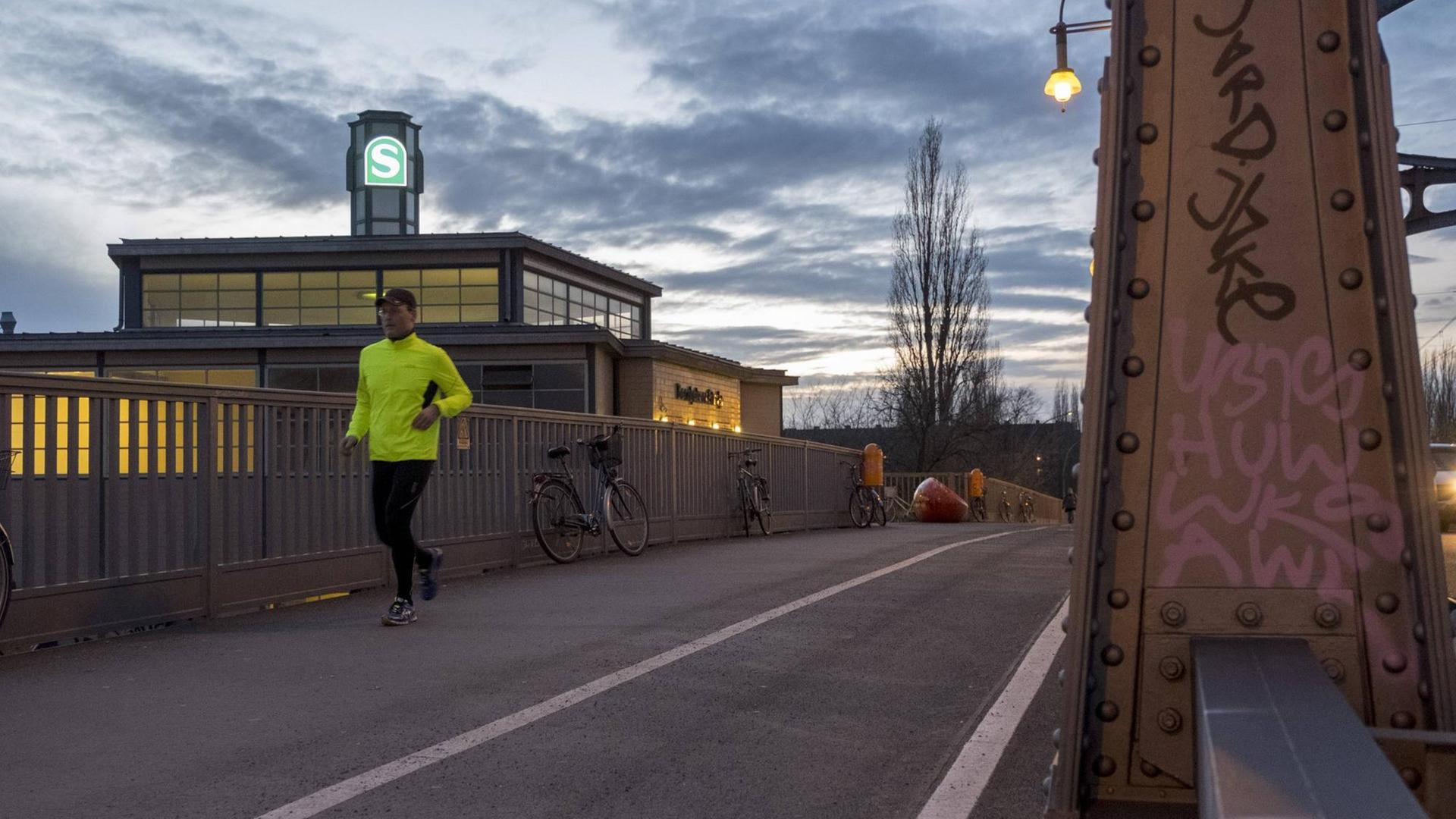 In Jogger mit einer neogelben Jackel läuft am Eingang zum S-Bahnhof Bornholmer Straße in Berlin vorbei. In Jogger mit einer neogelben Jackel läuft am Eingang zum S-Bahnhof Bornholmer Straße in Berlin vorbei.