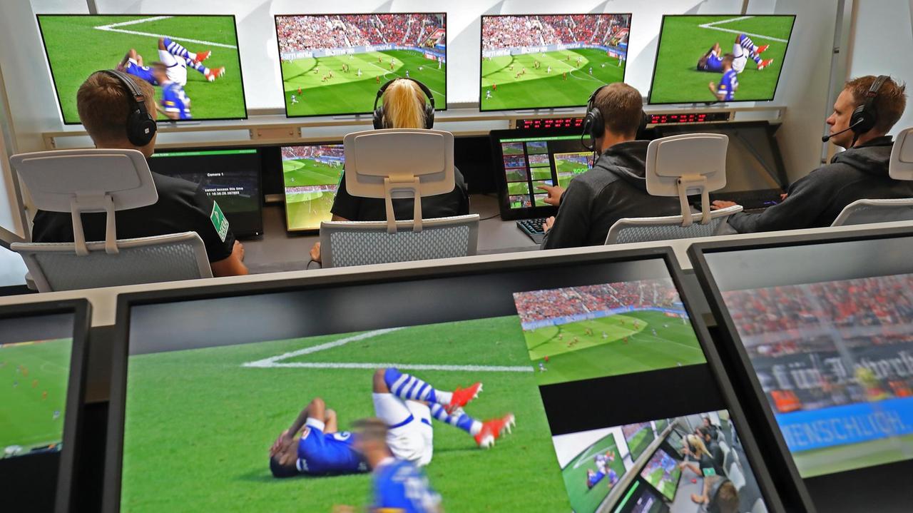 Fußball Schiedsrichter sitzen im Video-Assist-Center vor Monitoren. Fußball Schiedsrichter sitzen im Video-Assist-Center vor Monitoren.