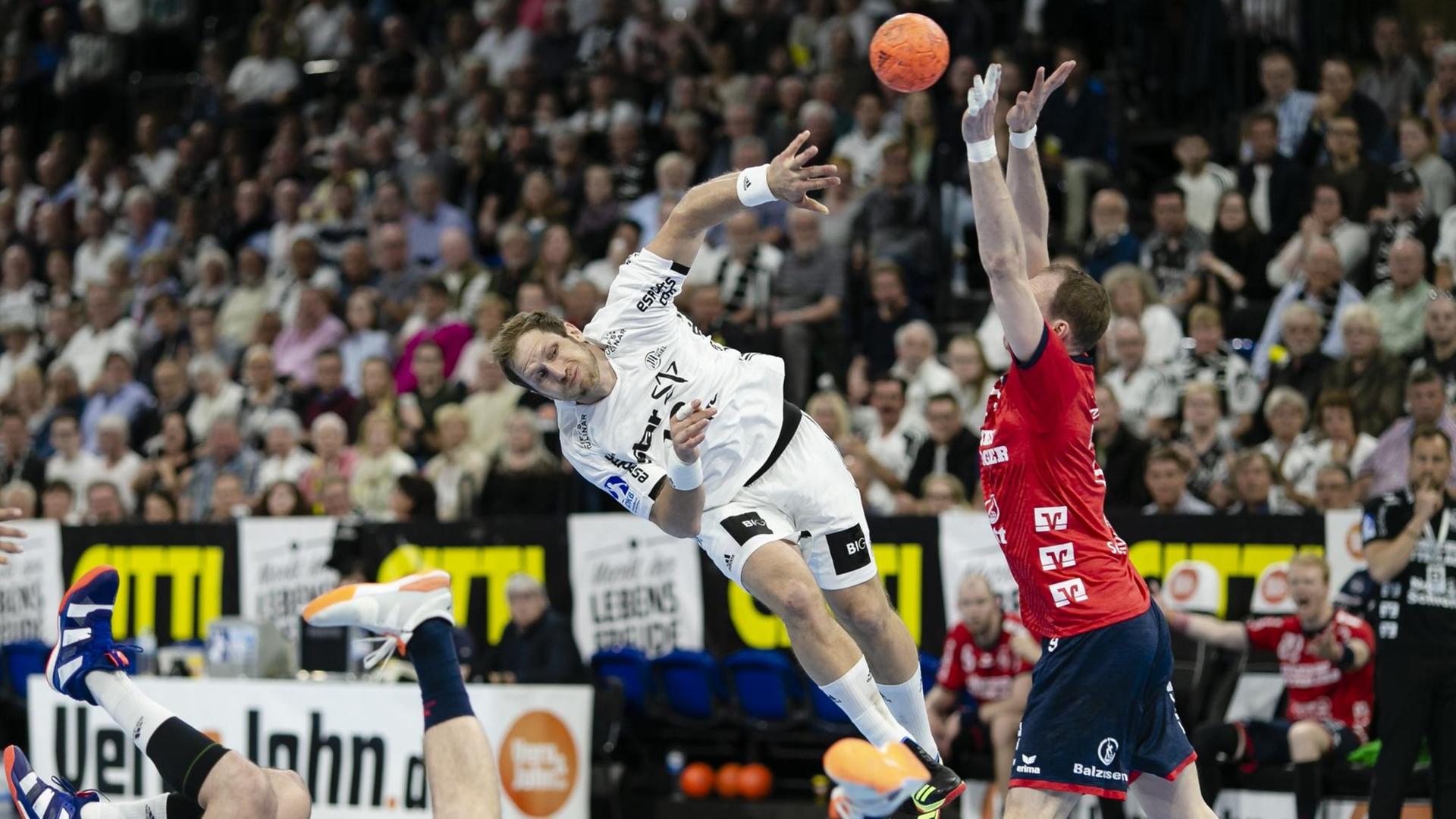 Ein Hand-Ball-Spieler aus Kiel (links) wirft einen Ball gegen einen Hand-Ball-Spieler aus Flensburg. Ein Hand-Ball-Spieler aus Kiel (links) wirft einen Ball gegen einen Hand-Ball-Spieler aus Flensburg.
