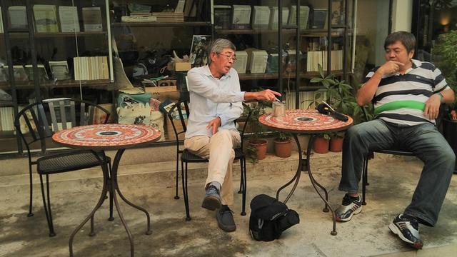 Buchhändler Lam Wing-kee vor einem Bücher-Café in seiner neuen Heimat Taiwan. Er raucht und spricht mit Journalisten.