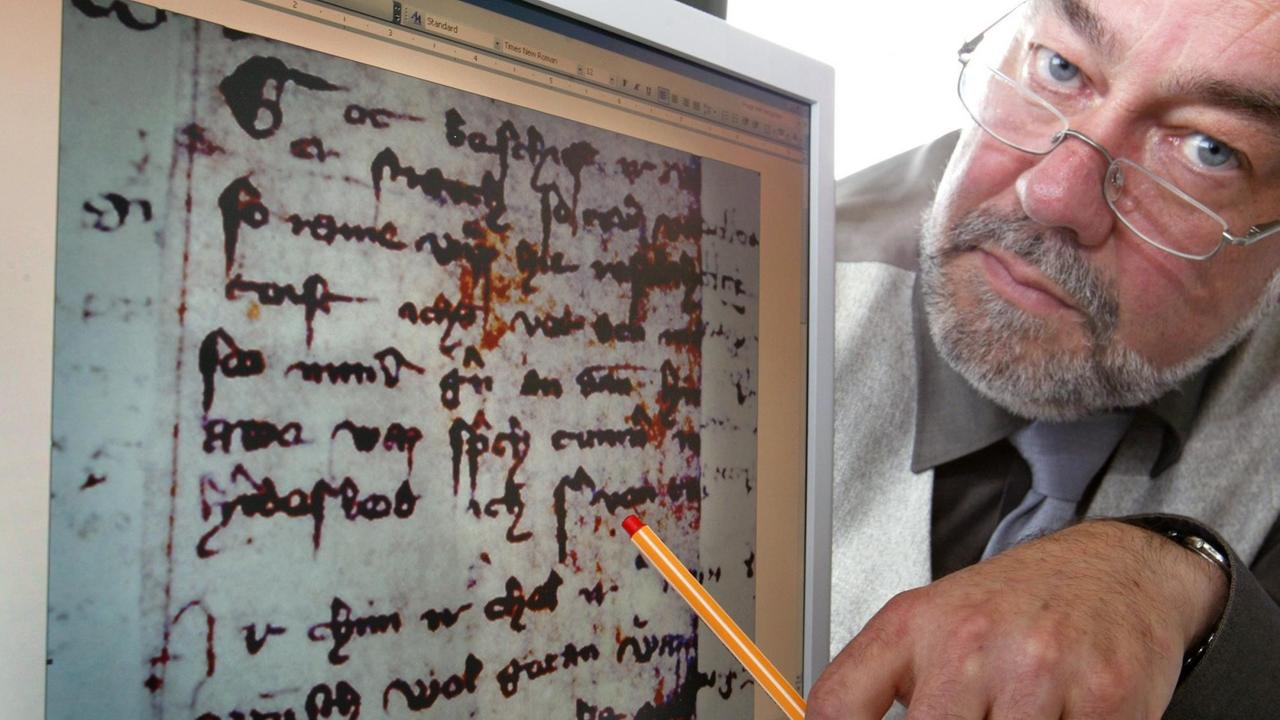Professor Freimut Löser deutet in der Augsburger Universität auf einen Monitor, auf dem die Reproduktion einer Handschrift aus dem 14. Jahrhundert abgebildet ist.
