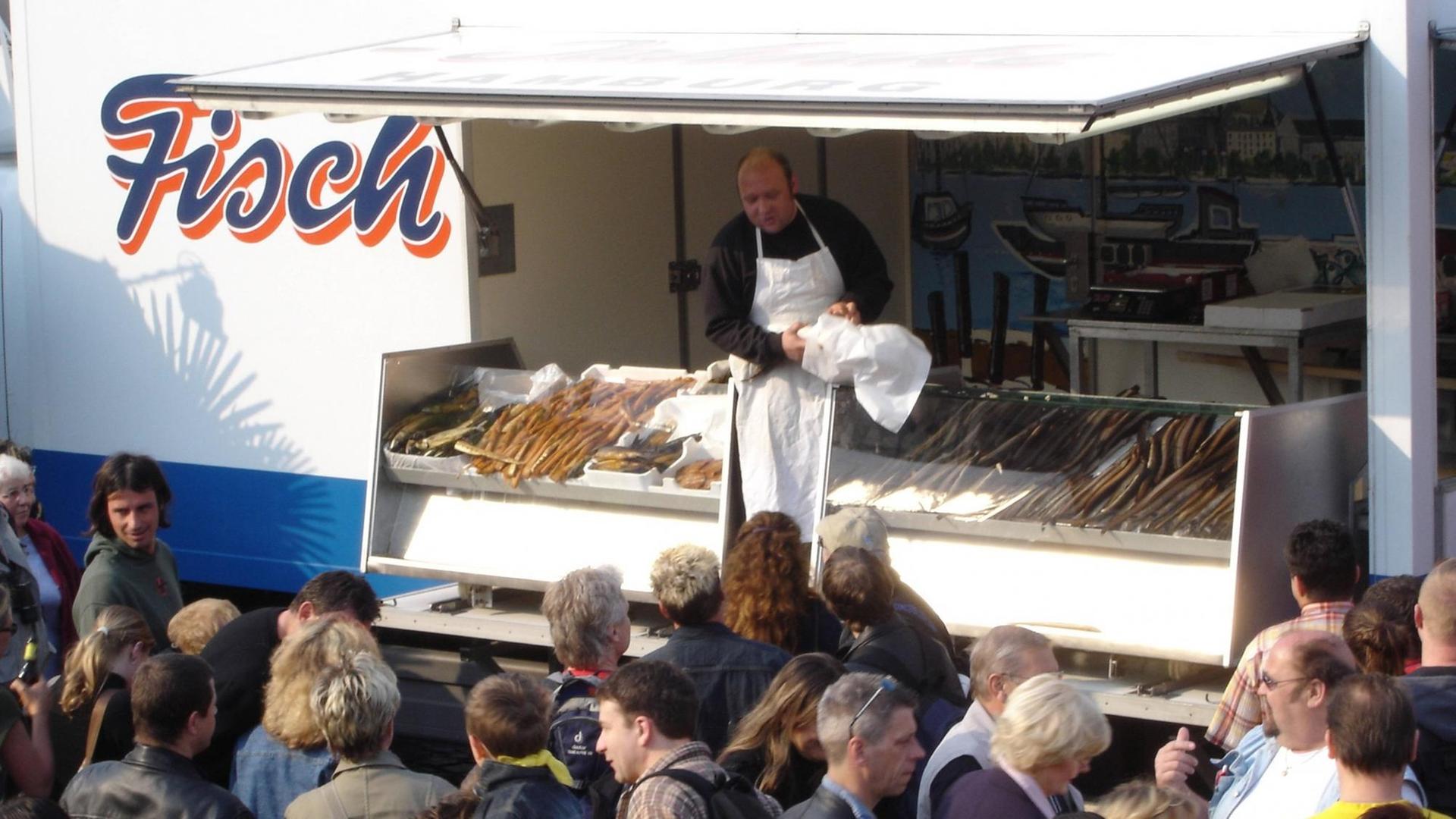 Besucher des Fischmarktes stehen vor dem Verkaufswagen eines Händlers. Besucher des Fischmarktes stehen vor dem Verkaufswagen eines Händlers.