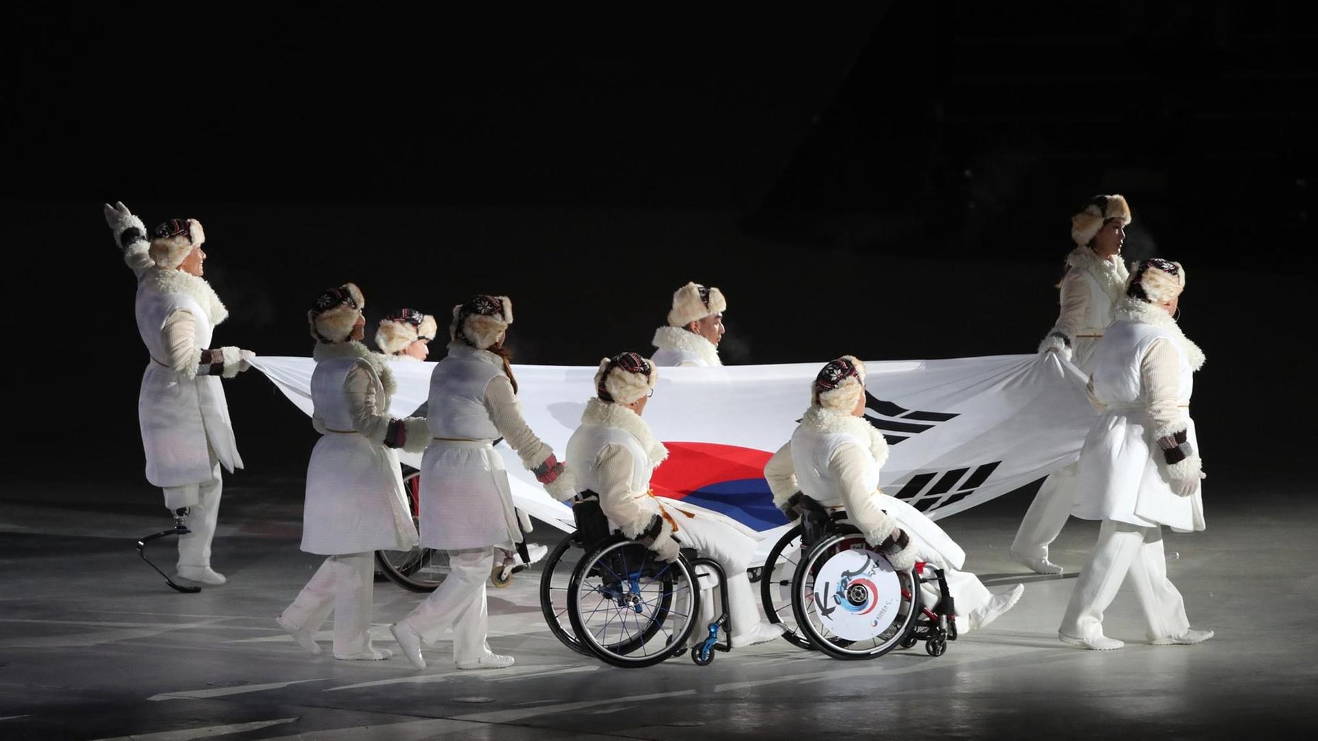 Ehemalige südkoreanische Medaillengewinner tragen eine Fahne bei der Paralympics-Eröffnungsfeier. Ehemalige südkoreanische Medaillengewinner tragen eine Fahne bei der Paralympics-Eröffnungsfeier.