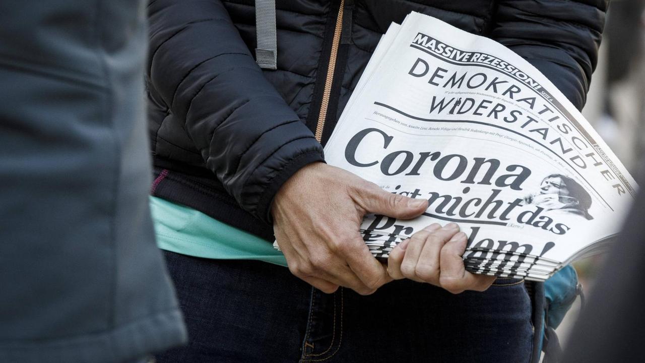 Demonstration gegen Corona-beschränkungen: Ein Demonstrant hält eine Zeitung des "Demokratischen Widerstands 2020"