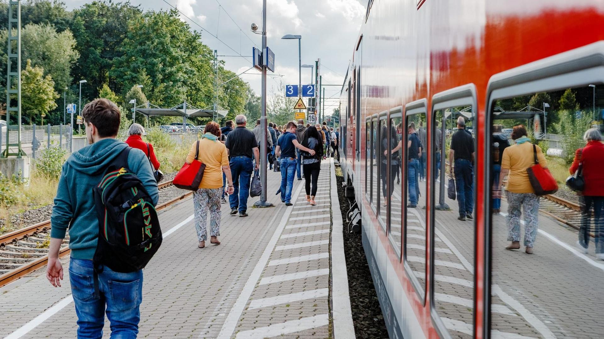 Bahnkunden gehen auf dem Bahnsteig an einem Regionalexpress der Deutschen Bahn (DB) entlang. Bahnkunden gehen auf dem Bahnsteig an einem Regionalexpress der Deutschen Bahn (DB) entlang.