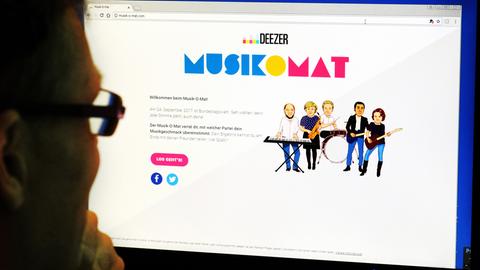 Ein Mann blickt auf einen Bildschirm, auf dem die Internetseite mit dem Musik-O-Mat zu sehen ist.