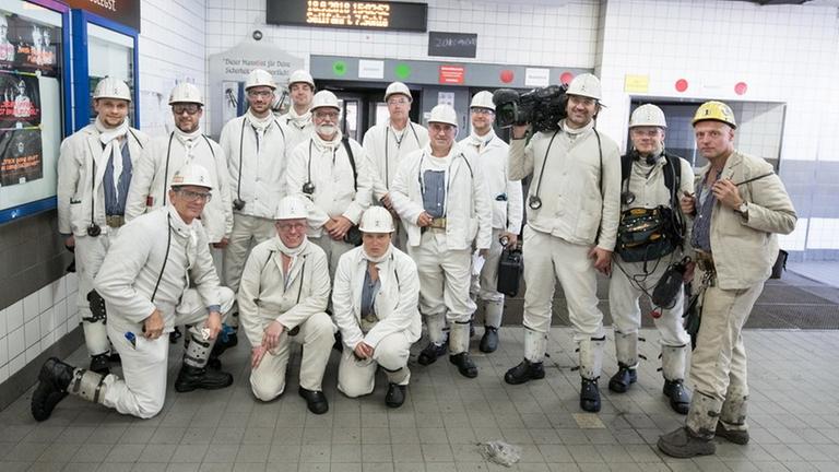 Gruppenbild einer Besuchergruppe in weißen Schutzanzügen 