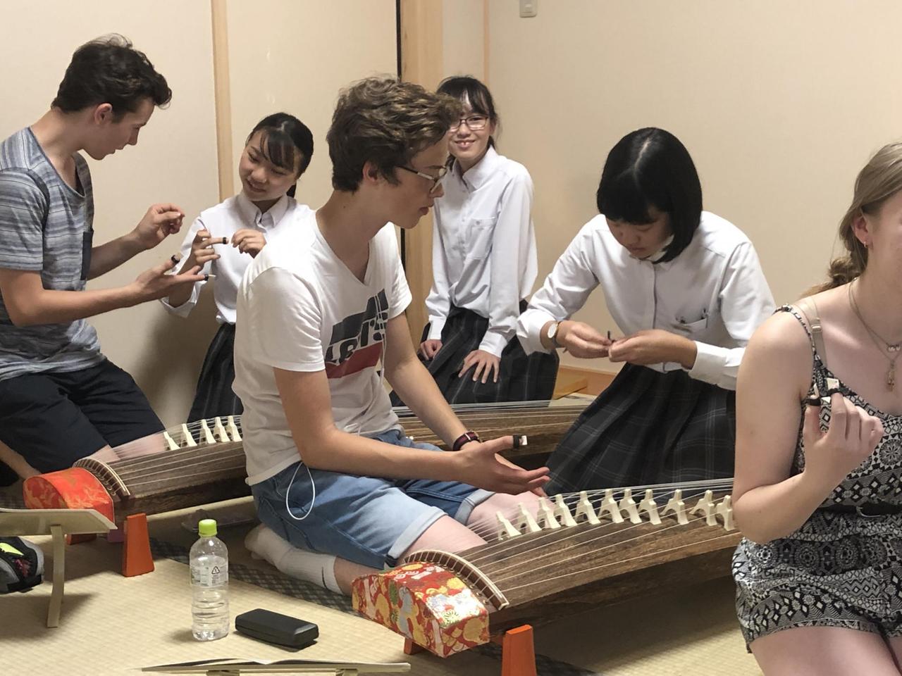 Junge Musiker und Musikerinnen über die Benutzung der Koto, einer Art japanischen Zither Junge Musiker und Musikerinnen über die Benutzung der Koto, einer Art japanischen Zither