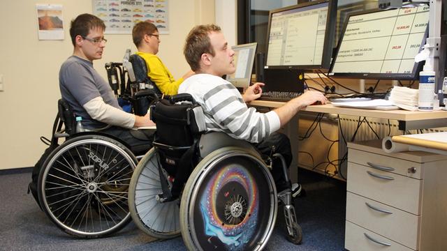 Mitarbeiter einer Behindertenwerkstatt der Diakonie Mitteldeutschland fertigen in Halle in Sachsen-Anhalt Aufsteller für Plakate.