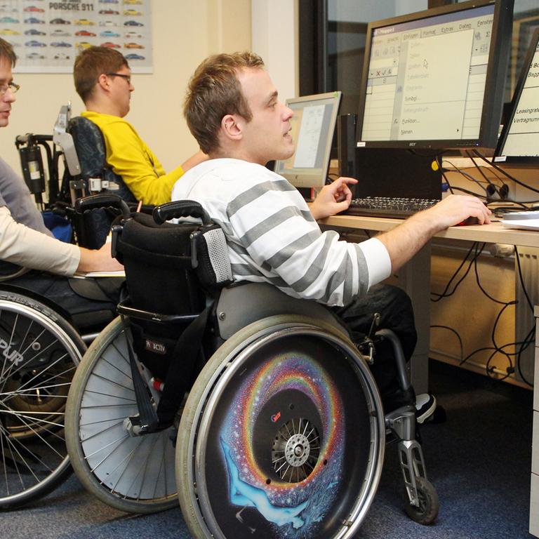 Mitarbeiter einer Behindertenwerkstatt der Diakonie Mitteldeutschland fertigen in Halle in Sachsen-Anhalt Aufsteller für Plakate.