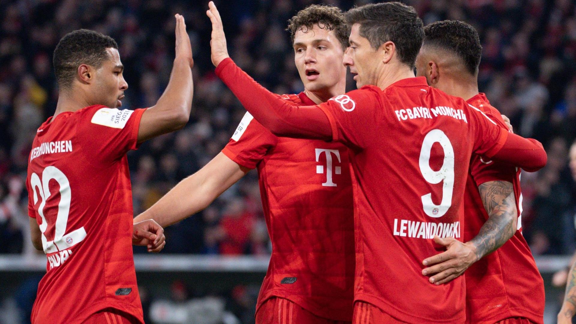 Vier Spieler umarmen sich jubelnd und klatschen sich ab. Vier Spieler umarmen sich jubelnd und klatschen sich ab.