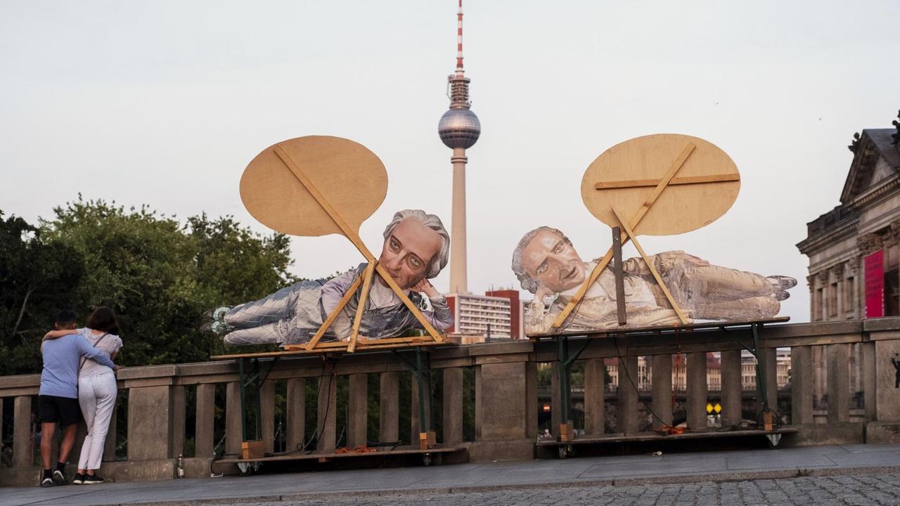 Werbung für ein Berliner Theater mittels Pappfiguren Goethe und Schiller an der Monbijoubrücke. Im Vordergrund ist ein junges Paar zu sehen. Dahinter der Fernsehturm. Werbung für ein Berliner Theater mittels Pappfiguren Goethe und Schiller an der Monbijoubrücke. Im Vordergrund ist ein junges Paar zu sehen. Dahinter der Fernsehturm.