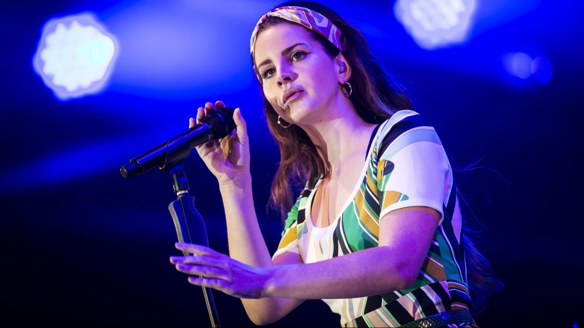 Lana Del Rey mit Mikrofon auf der Bühne. Lana Del Rey mit Mikrofon auf der Bühne.