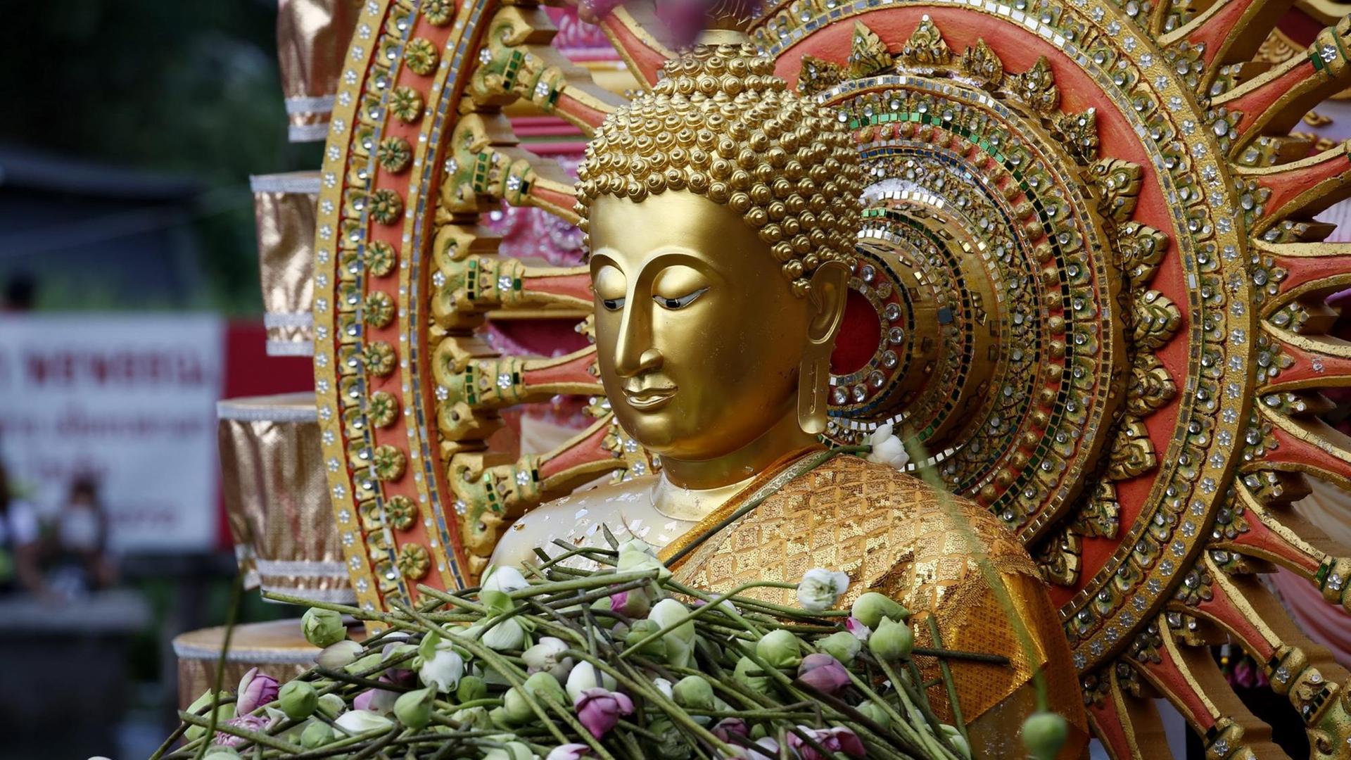 Ein Buddha in Bangkok, der im Rahmen einer religiösen Zeremonie mit Lotusblumen überhäuft ist Ein Buddha in Bangkok, der im Rahmen einer religiösen Zeremonie mit Lotusblumen überhäuft ist