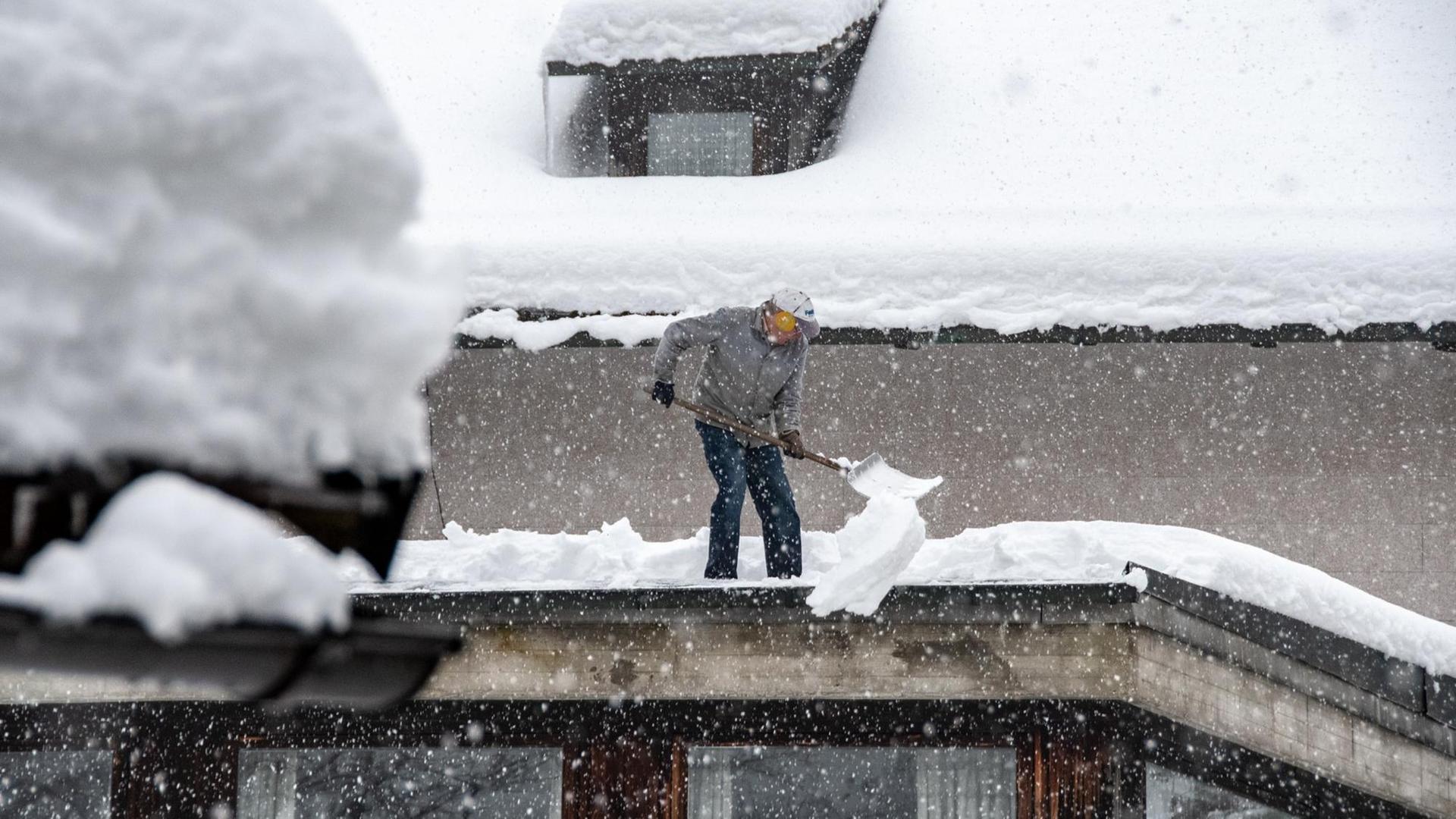 13.01.2019, Bayern, Elisabethszell: Ein Mann schaufelt Schnee von einem Dach.