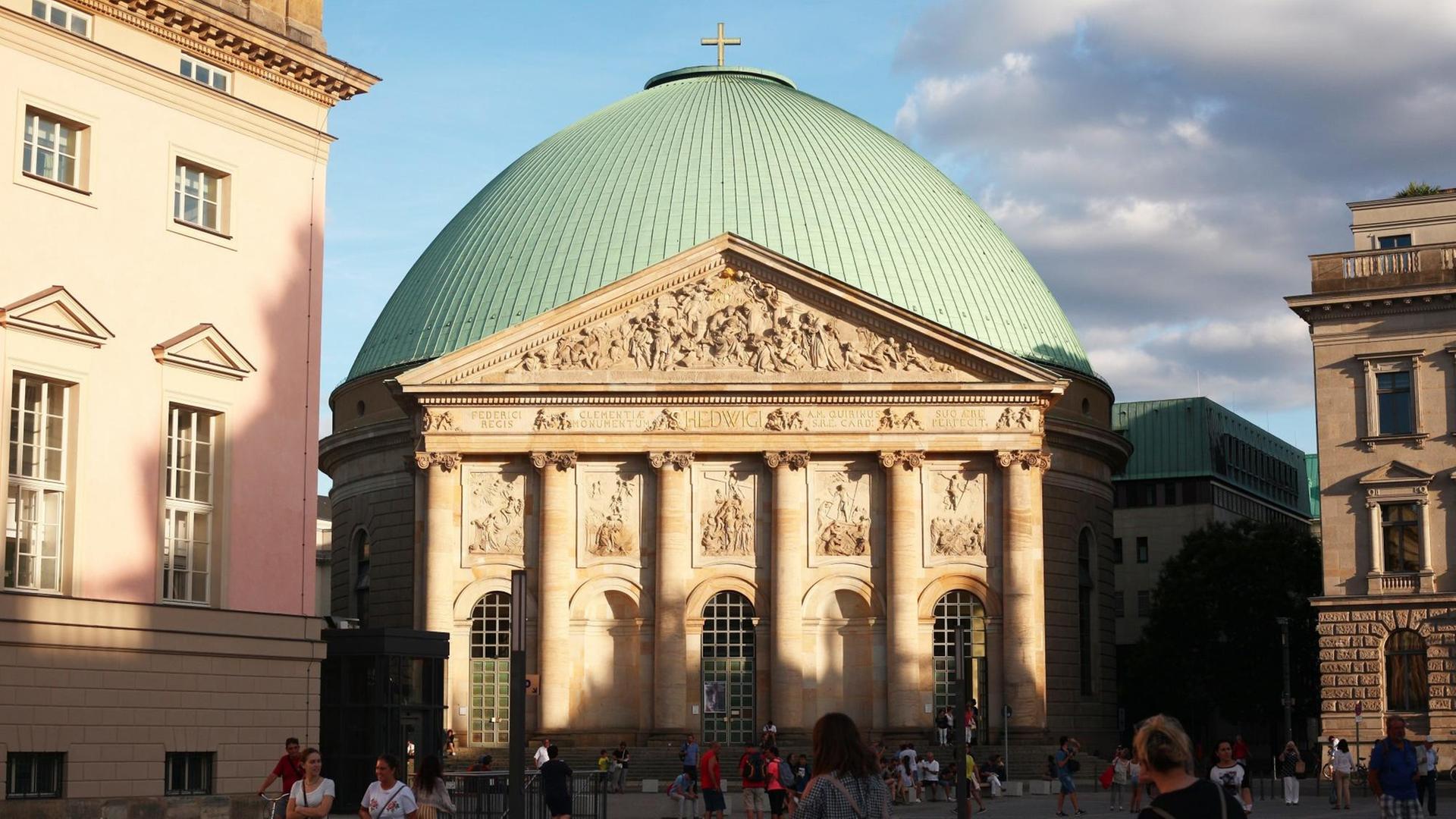 Menschen gehen am 12.08.2018 in Berlin im Bezirk Mitte über den Platz vor der St. Hedwigs-Kathedrale.