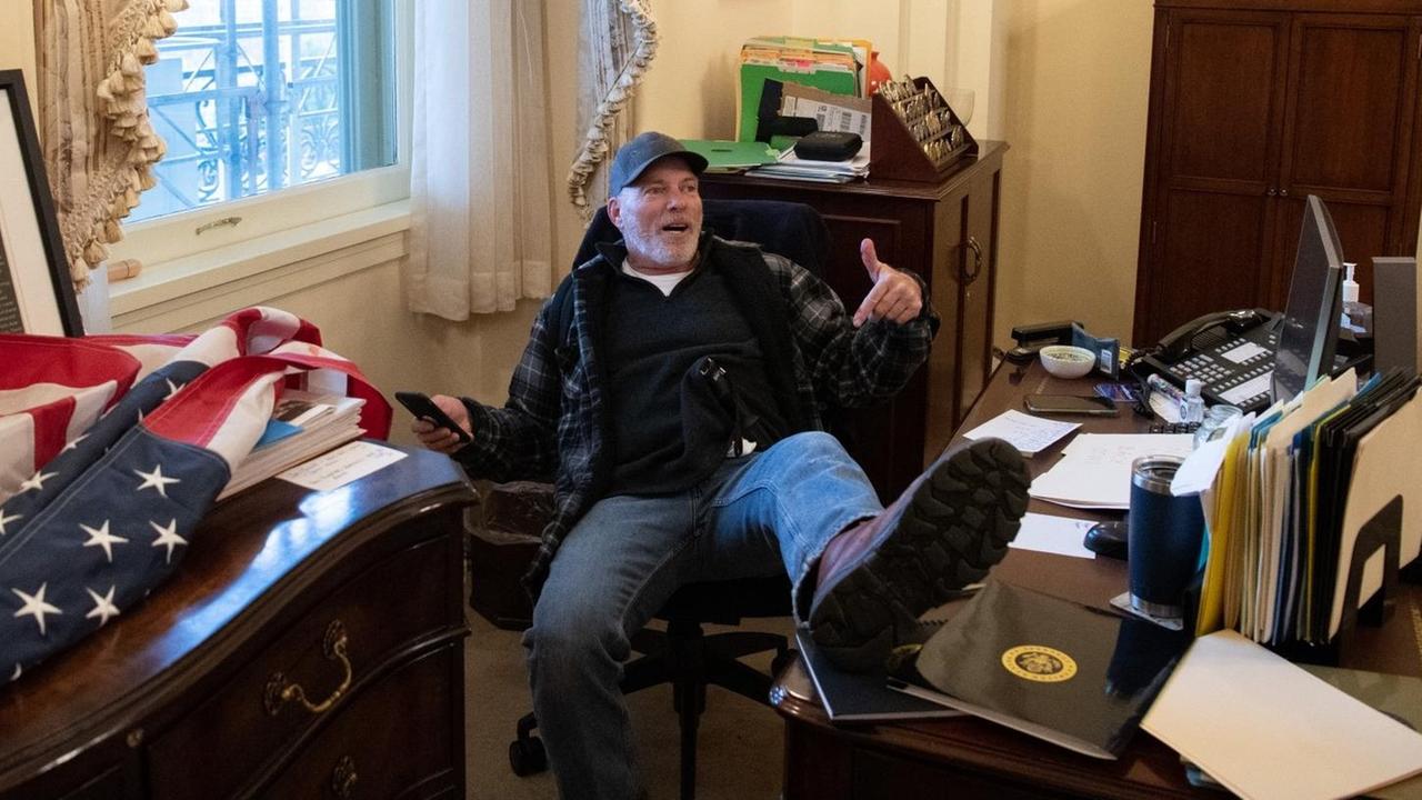 Ein Demonstrant sitzt am Schreibtisch von Nancy Pelosi. Ein Demonstrant sitzt am Schreibtisch von Nancy Pelosi.