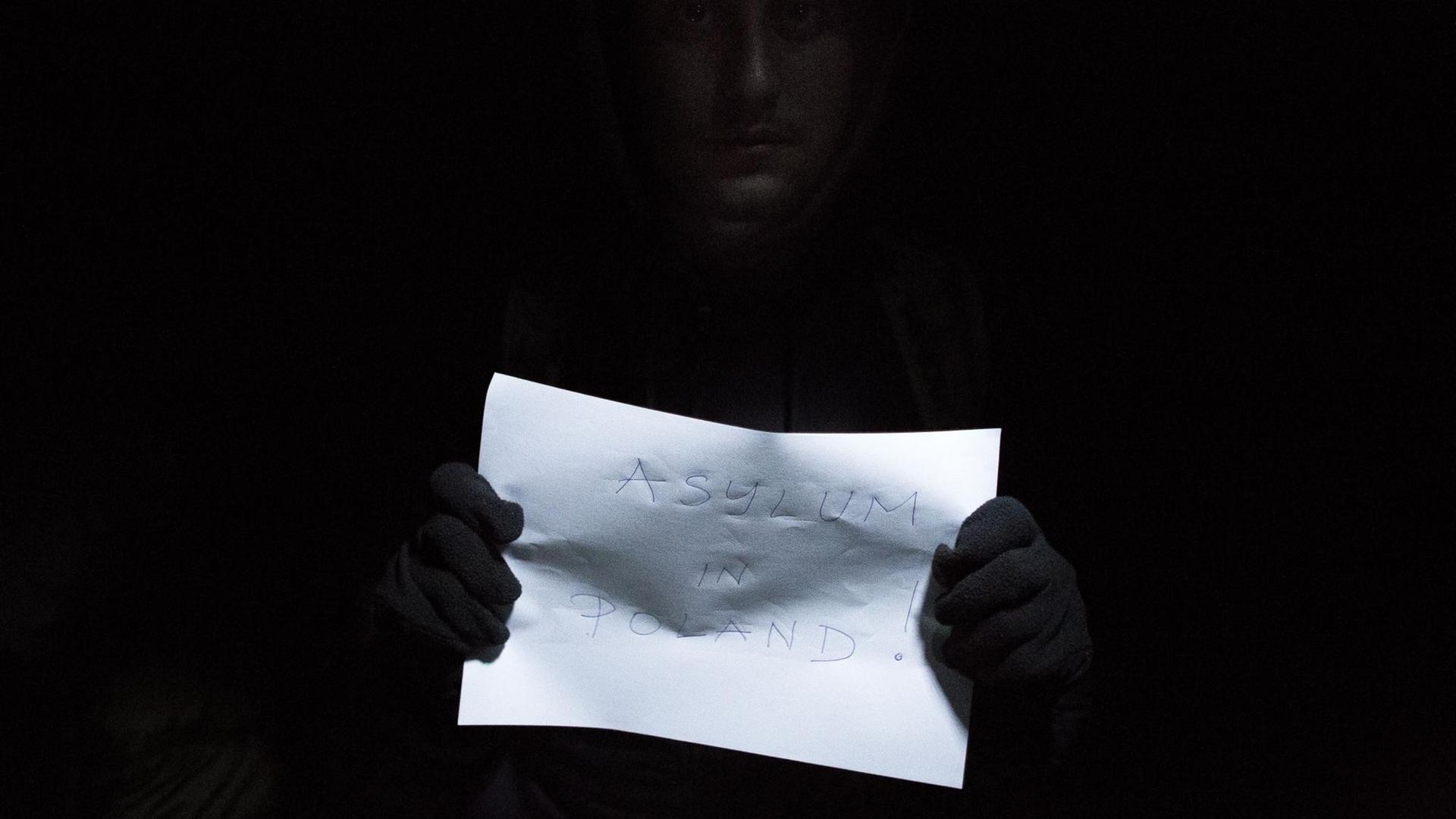 Ein Flüchtling hält ein Papier mit der Aufschrift "Asyl in Polen" in der Hand, während er einen Asylantrag stellt, nachdem er die polnisch-belarussische überquert hat. Ein Flüchtling hält ein Papier mit der Aufschrift "Asyl in Polen" in der Hand, während er einen Asylantrag stellt, nachdem er die polnisch-belarussische überquert hat.
